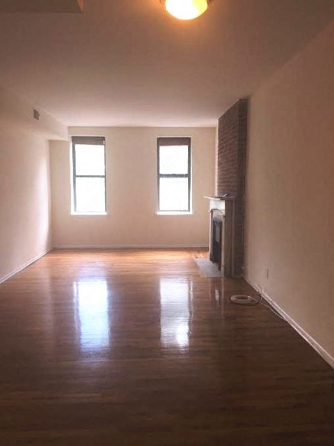 A room with wooden floors and two windows.