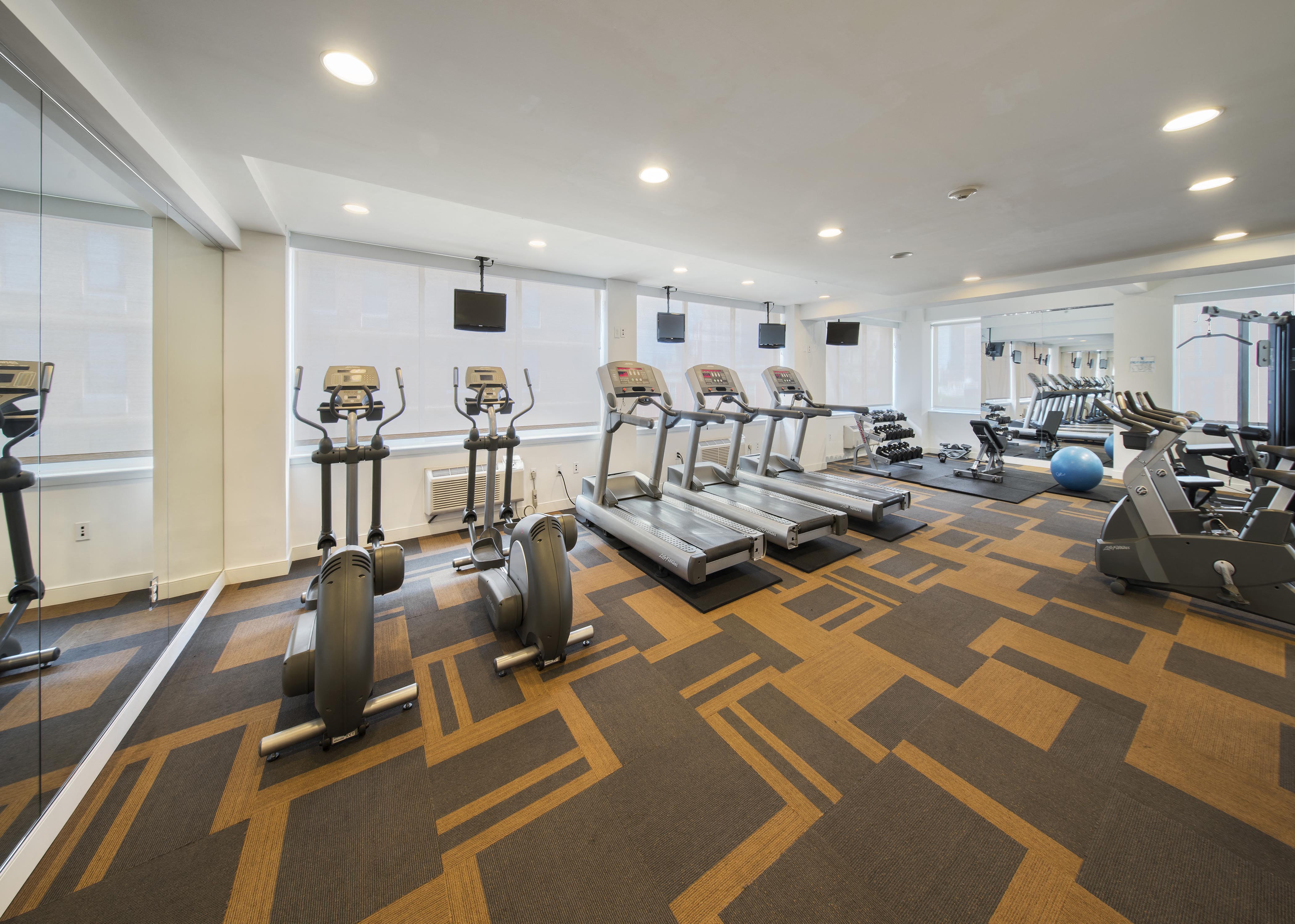 a gym with treadmills and weights on a carpeted floor