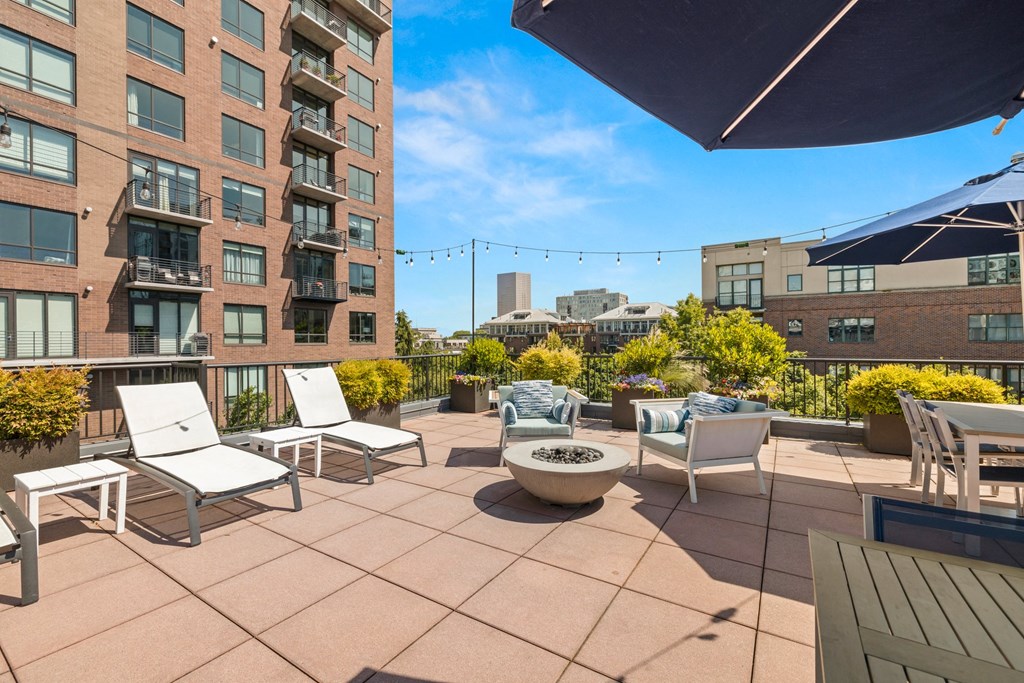 a rooftop patio with chairs and a fire pit