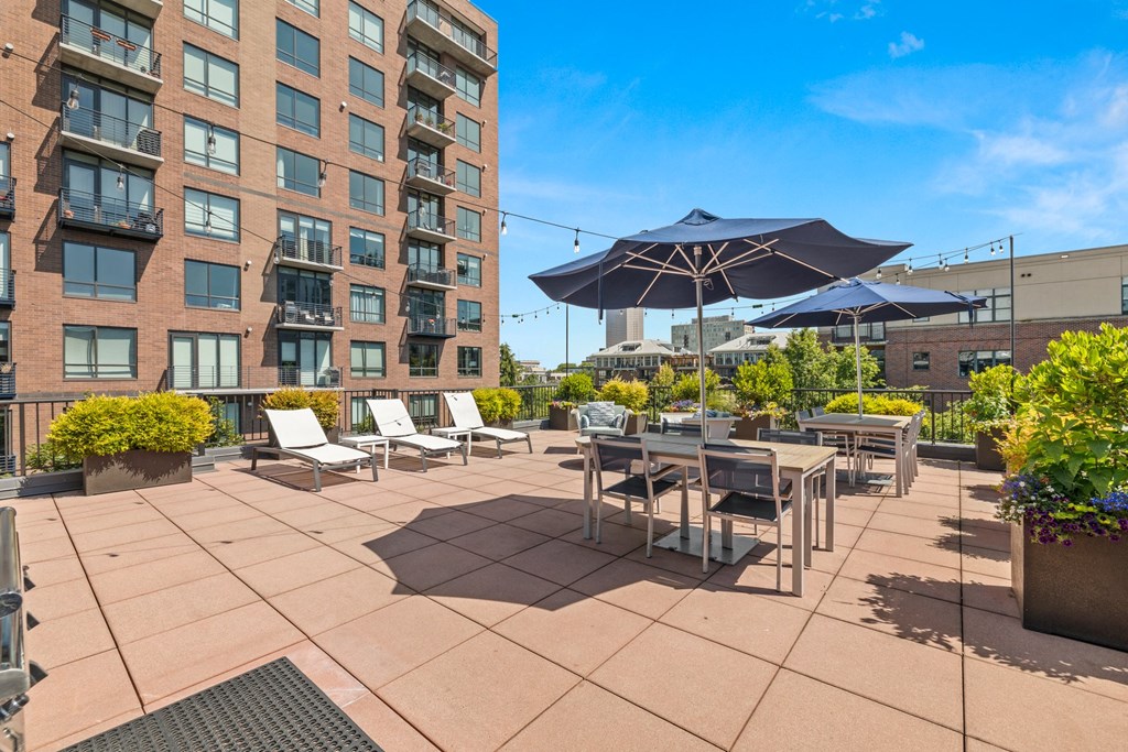 a patio with chairs tables and umbrellas and a building in the background