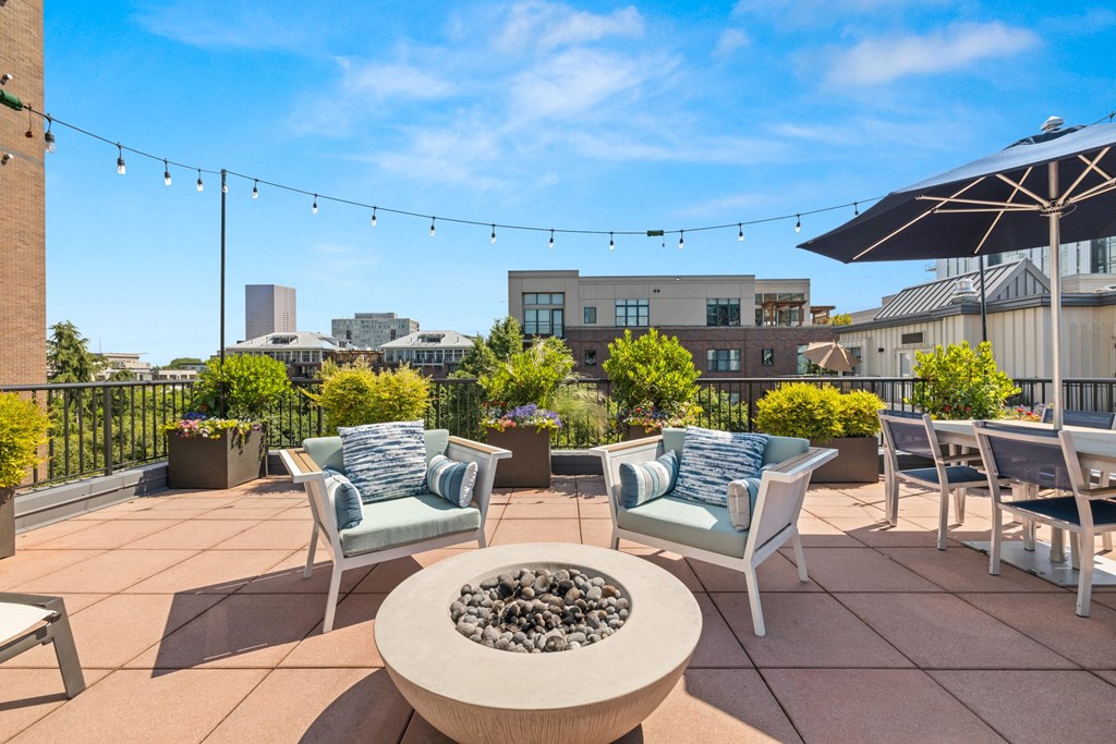 a rooftop patio with chairs and tables and a fire pit