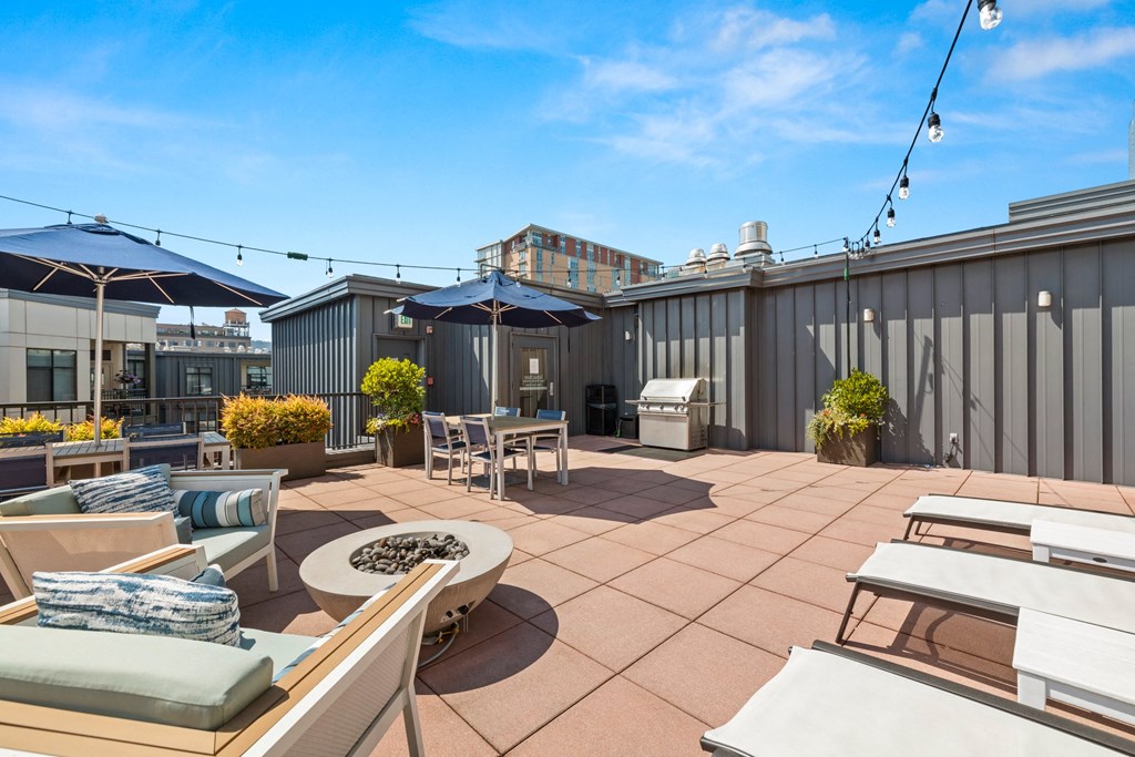 a rooftop patio with tables and chairs and umbrellas