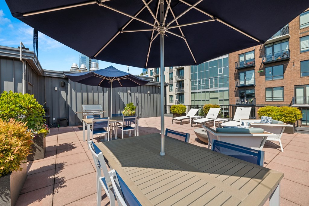 a patio with tables with umbrellas and chairs and a building in the background