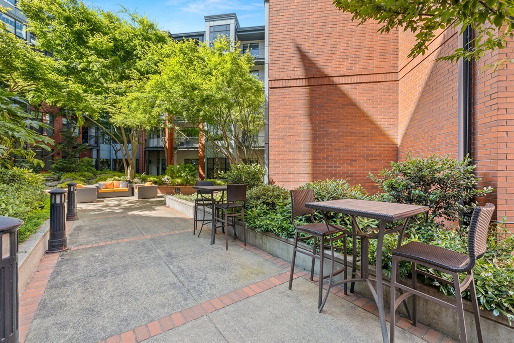 a patio with tables and chairs in front of a brick building