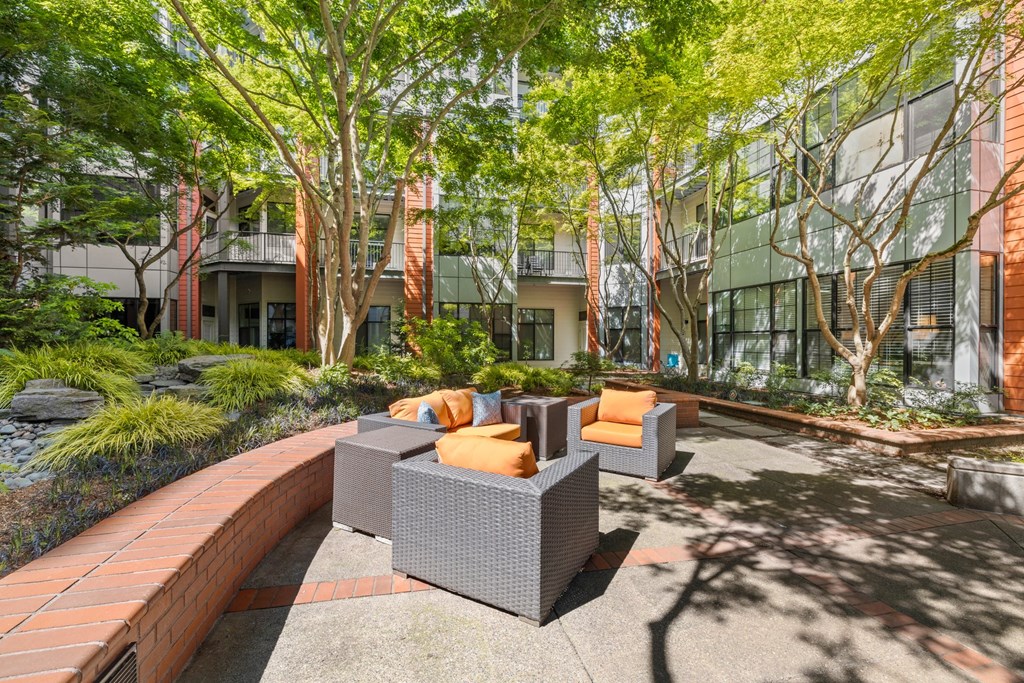 a courtyard with furniture and trees in front of a building