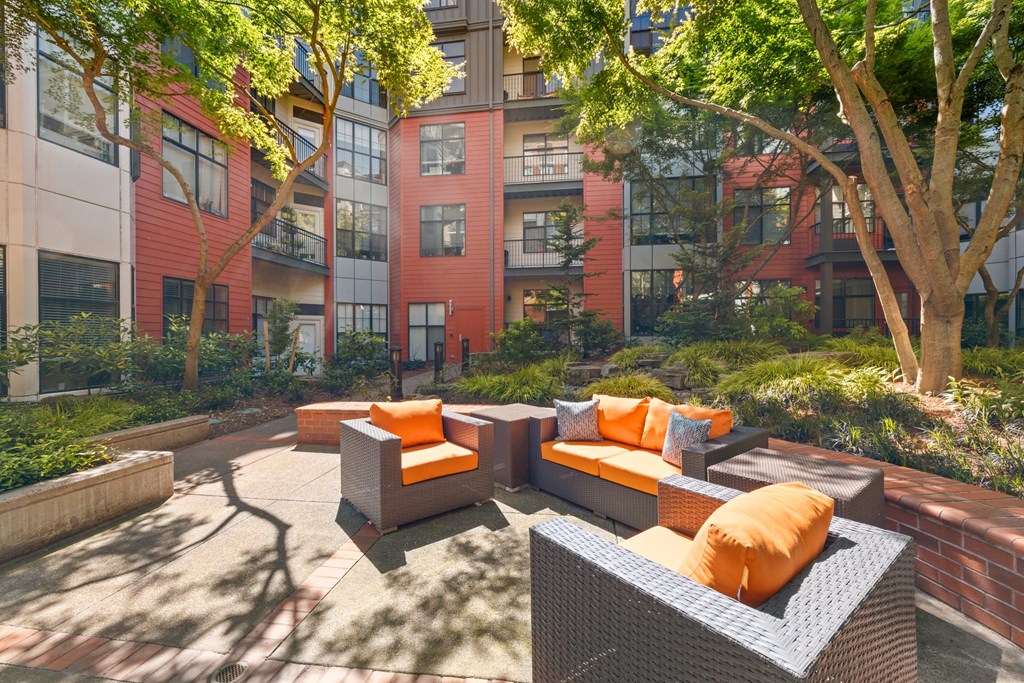 a courtyard with couches and trees in front of an apartment building