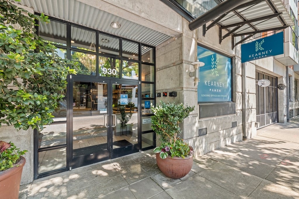 the entrance to a building with glass doors and a potted plant