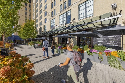 People walking on a sidewalk with a building in the background.
