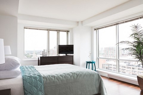 a bedroom with a bed and a tv and some windows