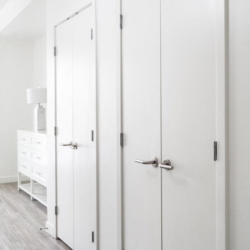 a row of white closet doors in a white bedroom