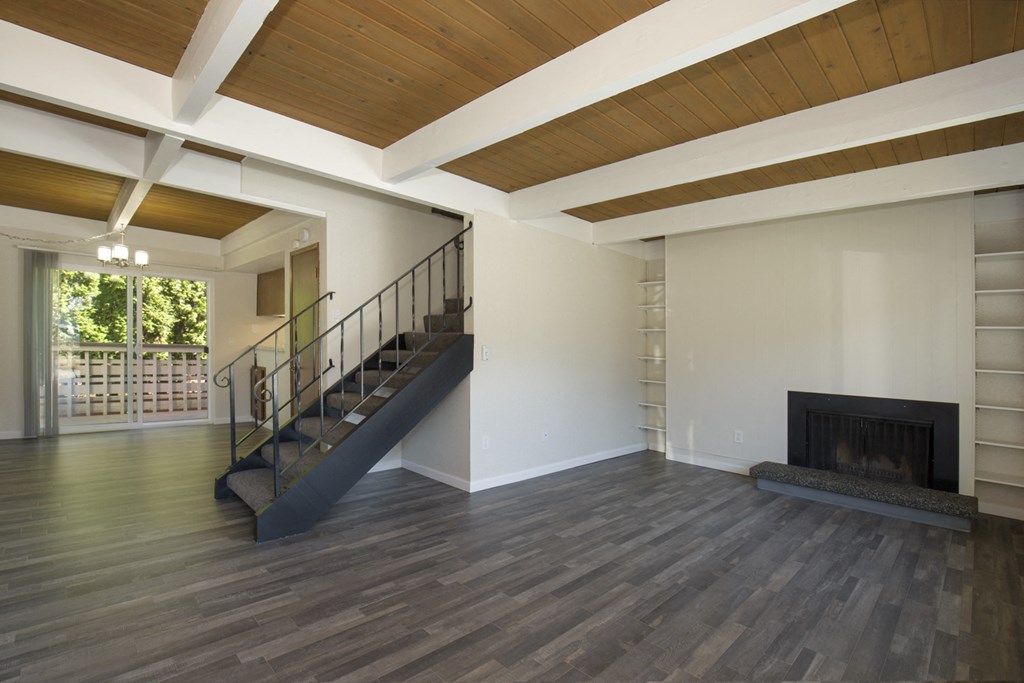 Spacious Living Room with Plank Flooring, Overhead Exposed Beams, Iron Staircase, and Fireplace at Woodlake Townhomes, Washington, 98026