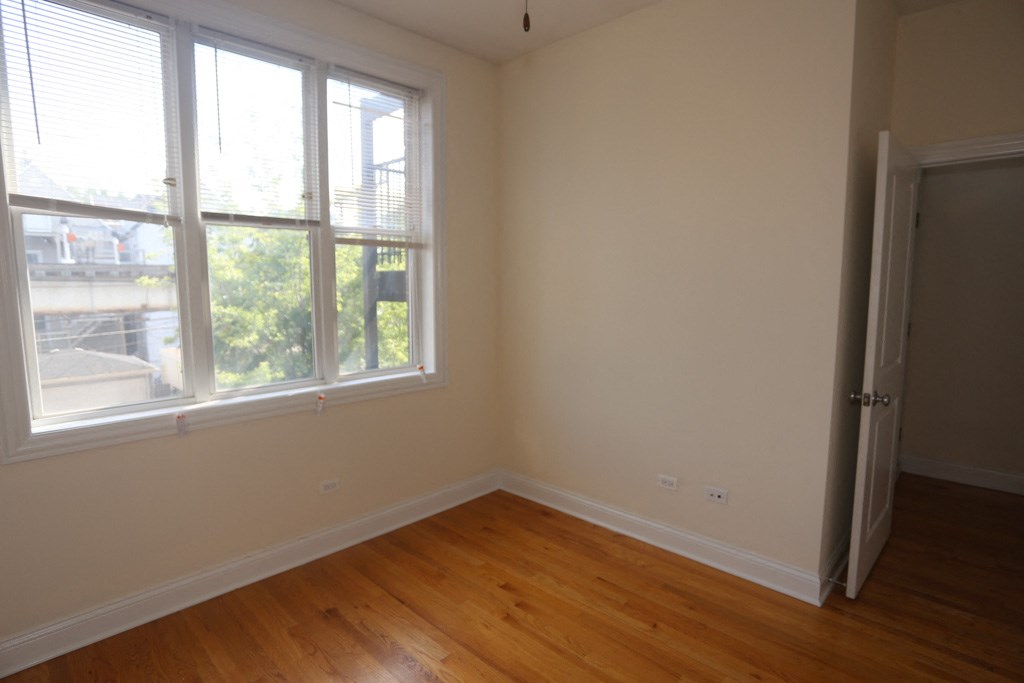 an empty room with wooden floors and two windows