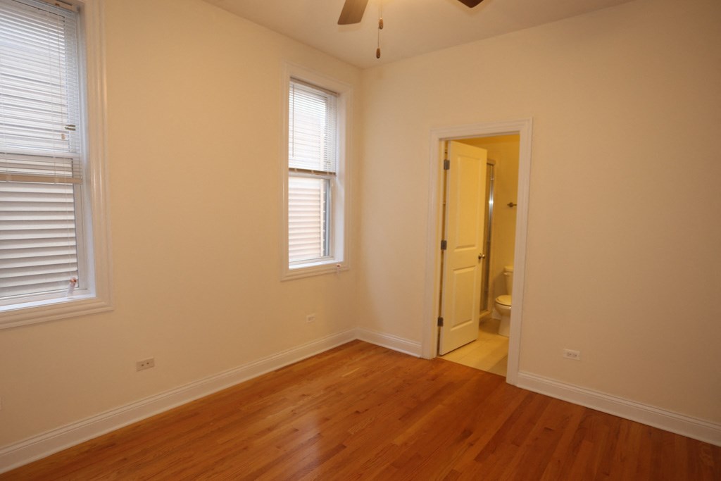 a bedroom with a wooden floor and a door to a bathroom