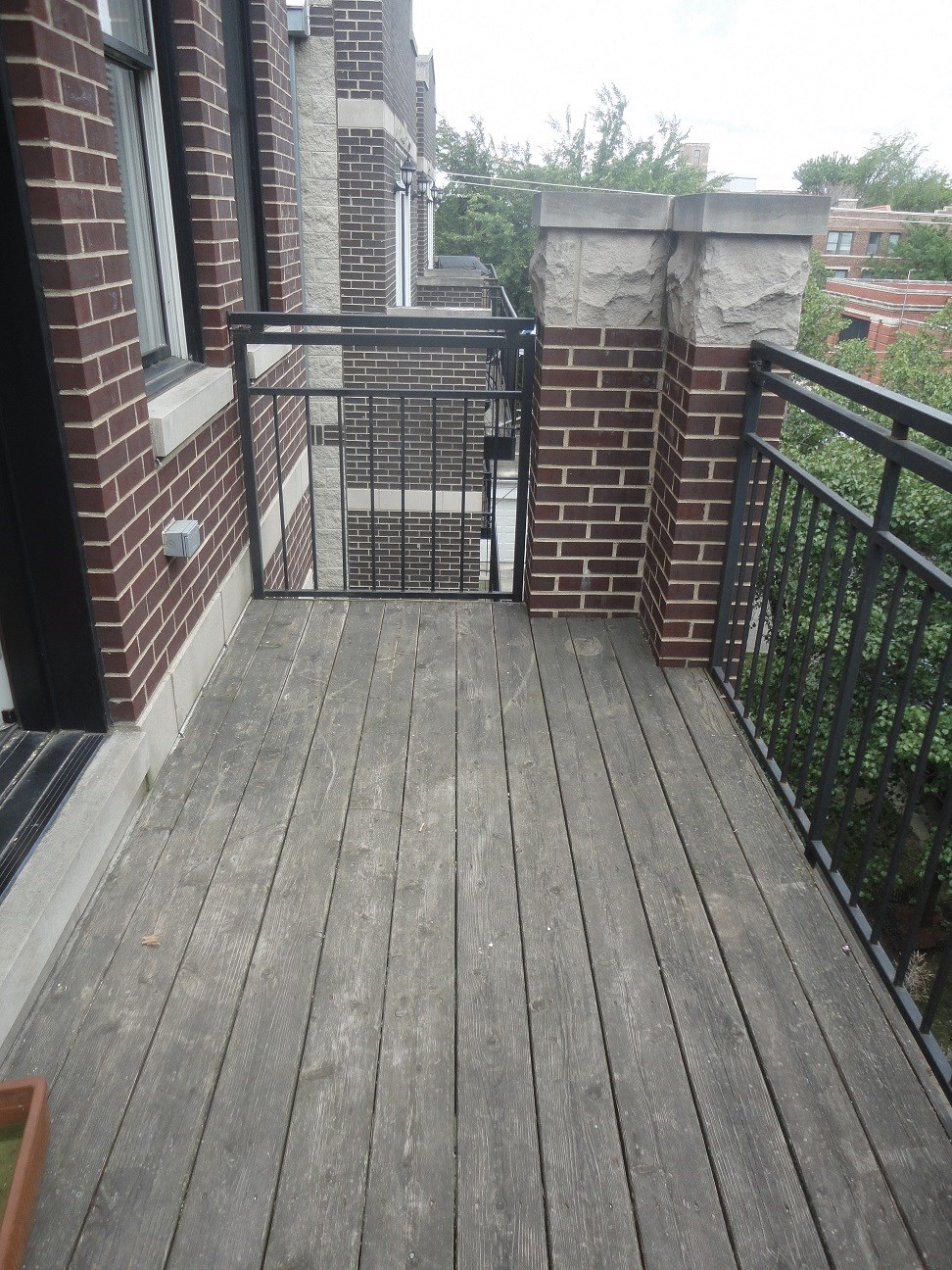 a balcony with a wooden deck and a brick wall