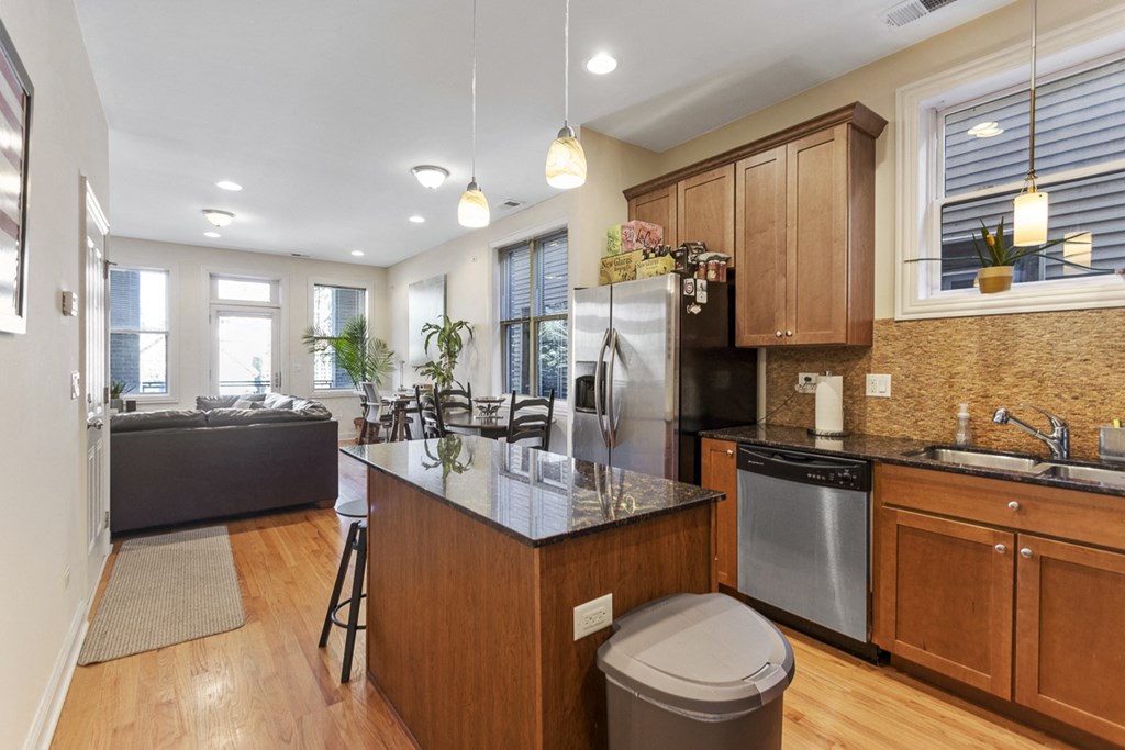 the kitchen and living room of a house with wooden cabinets and stainless steel appliances
