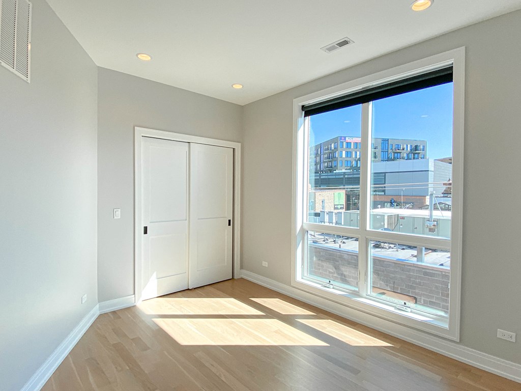 an empty living room with a large window and a door to a balcony