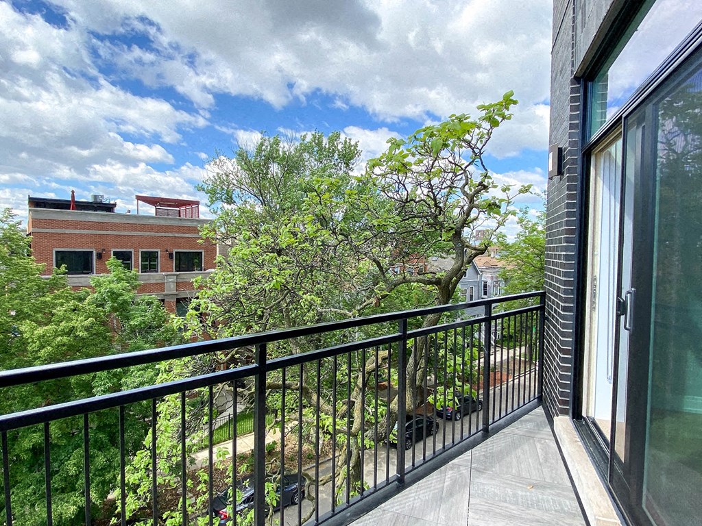 a balcony with a view of a tree and some buildings