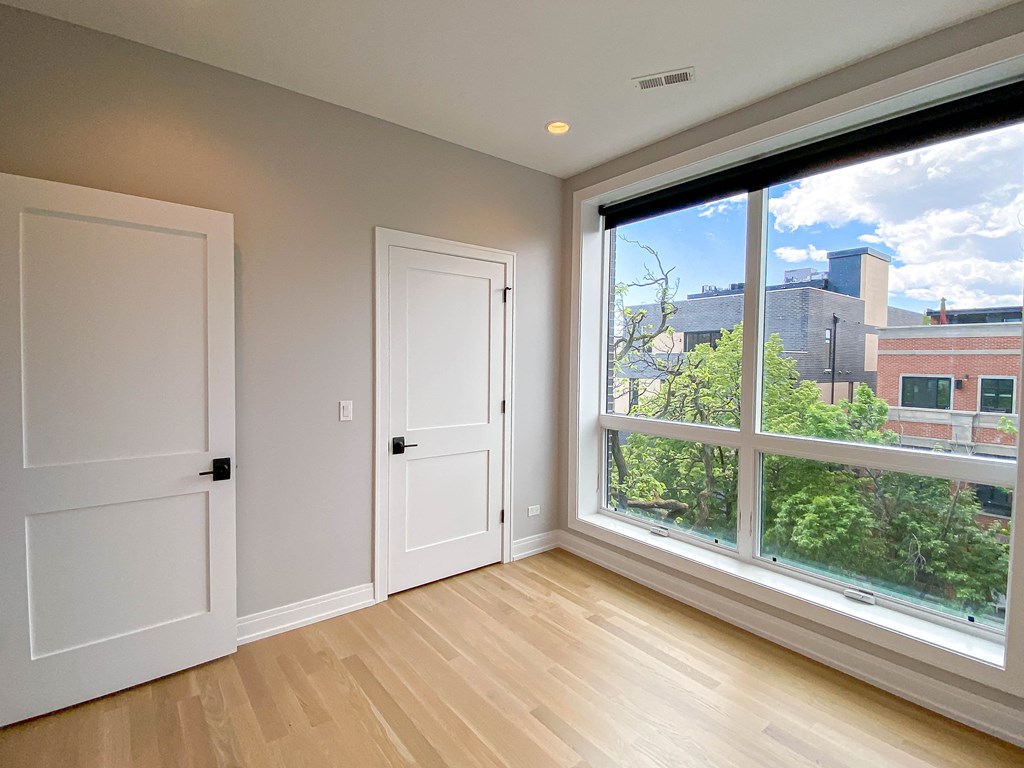 a bedroom with a large window and two doors and a wooden floor