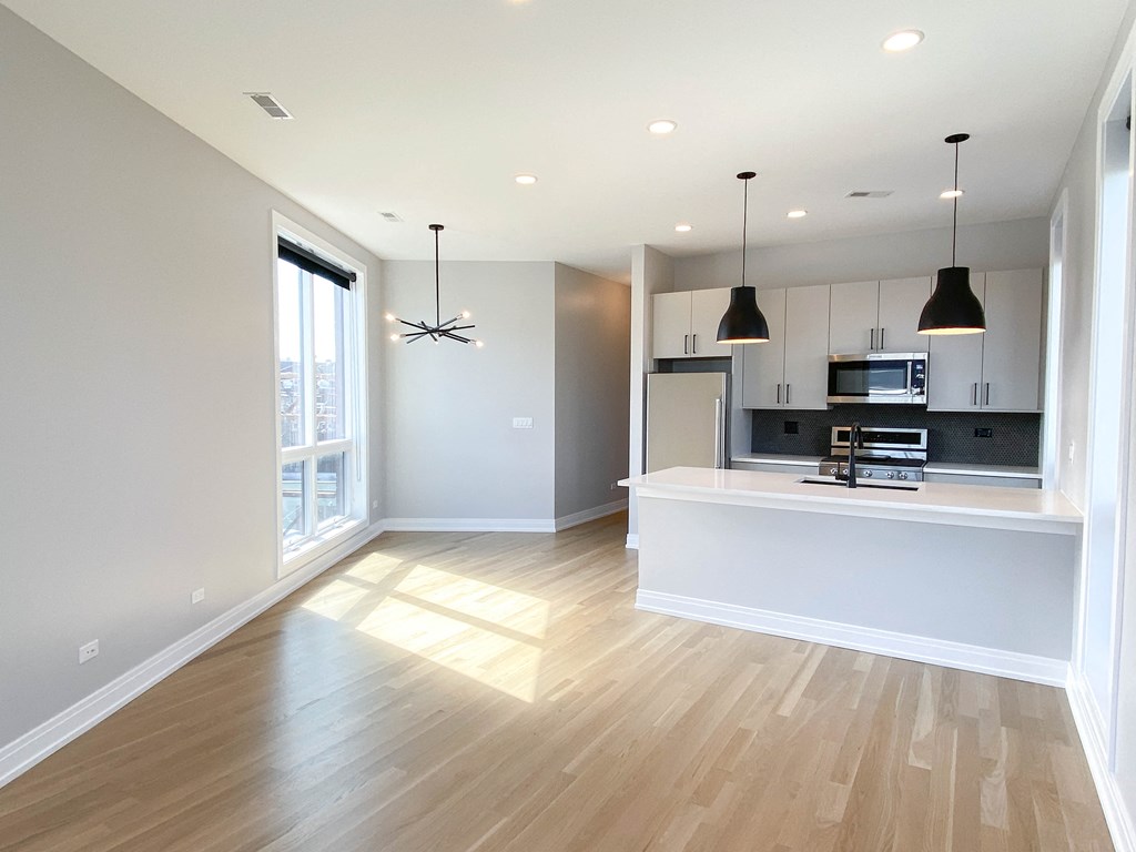 an open kitchen and living room with white walls and wood floors