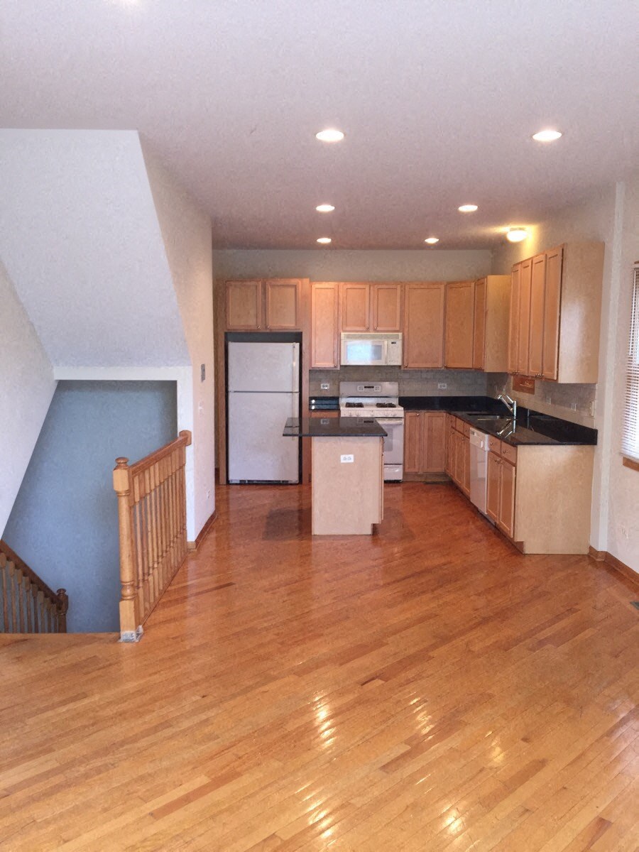 an empty kitchen and living room with a wooden floor