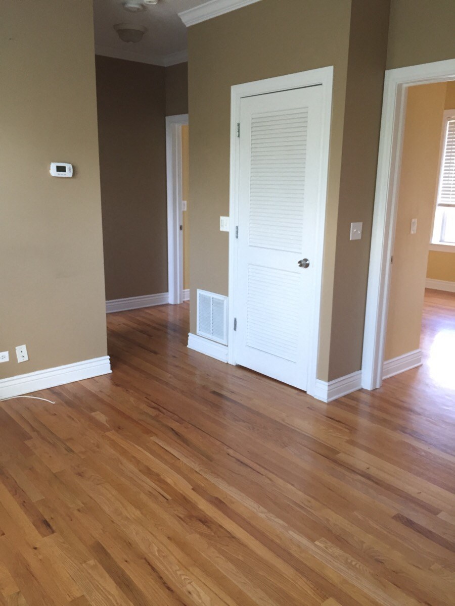 an empty living room with wooden floors and a white door