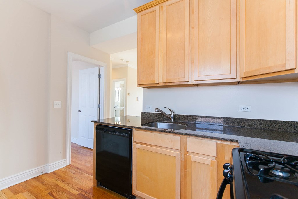 a kitchen with wooden cabinets and a black dishwasher