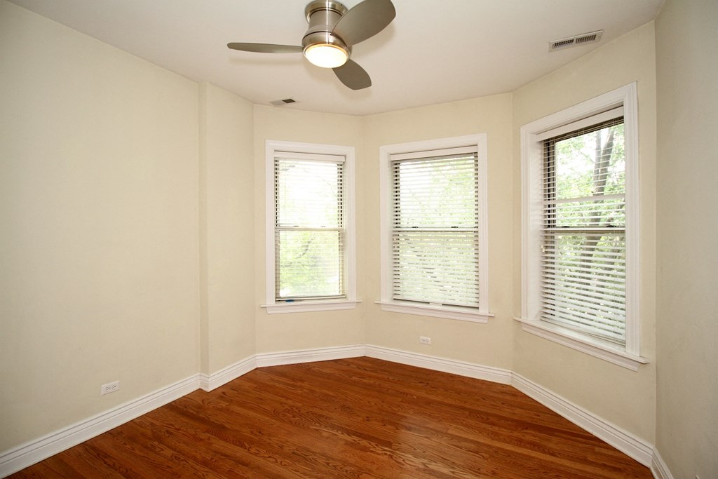 an empty room with a ceiling fan and three windows