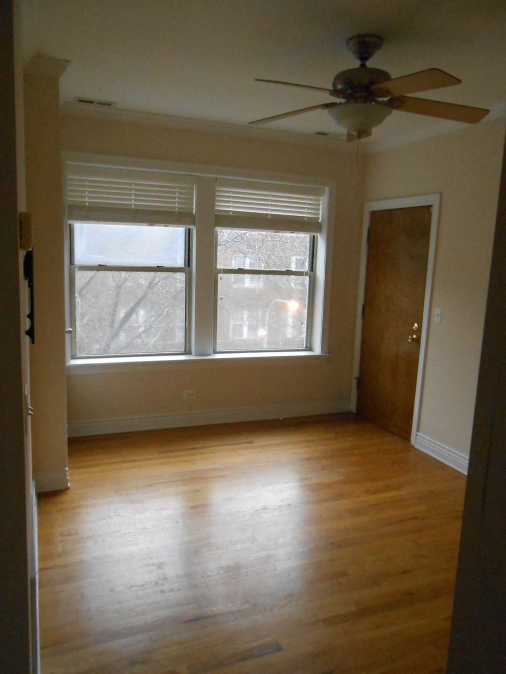 an empty living room with a ceiling fan and two windows
