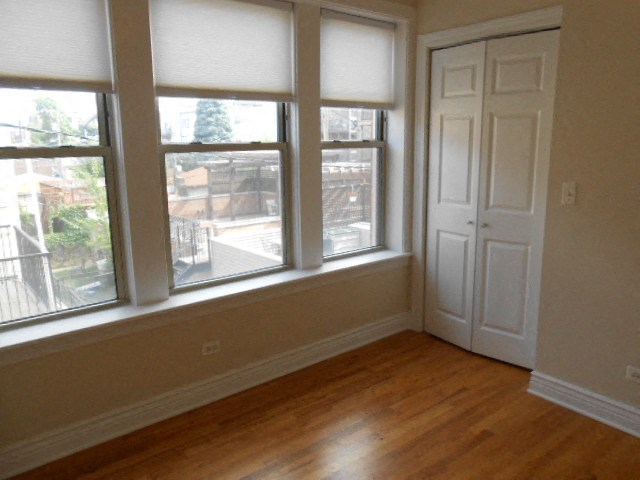 a living room with a wooden floor and three windows
