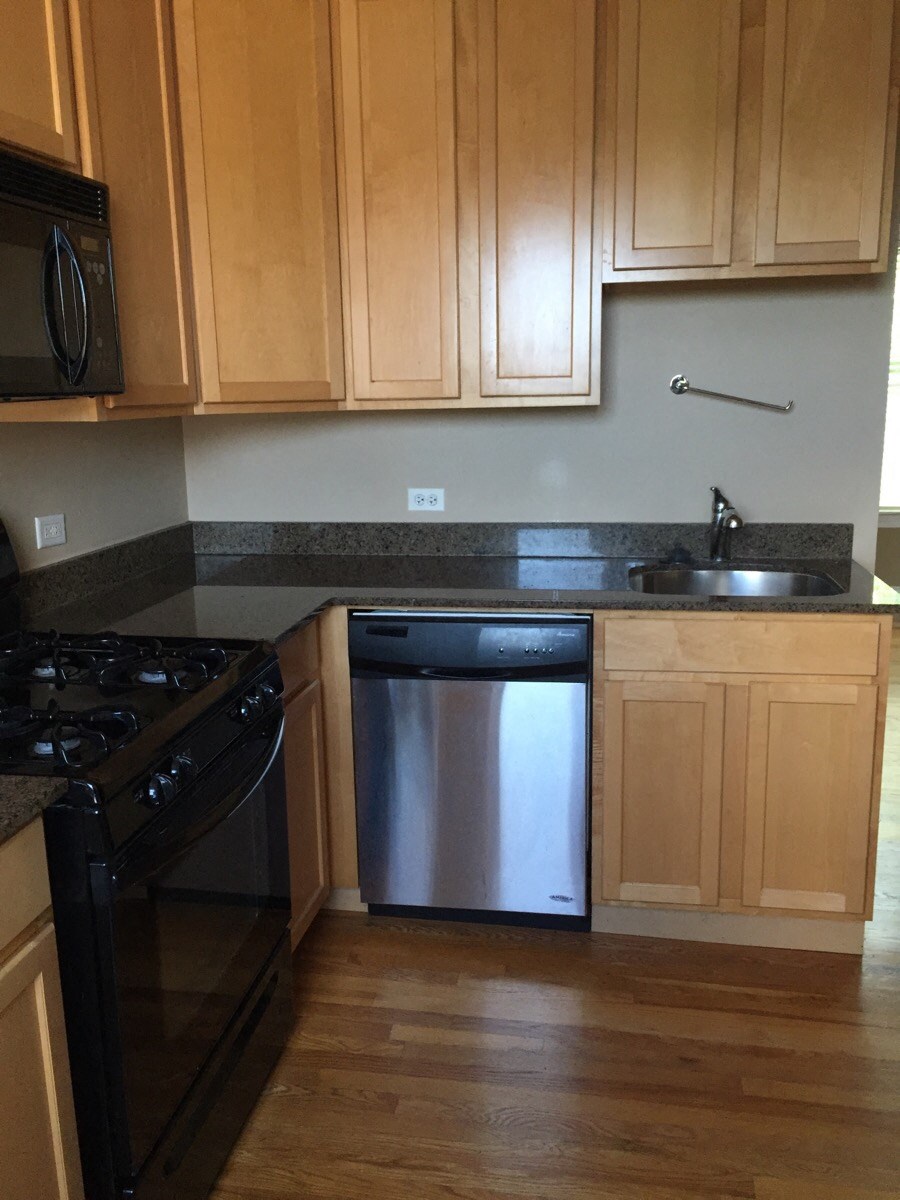 a kitchen with wooden cabinets and a stainless steel dishwasher