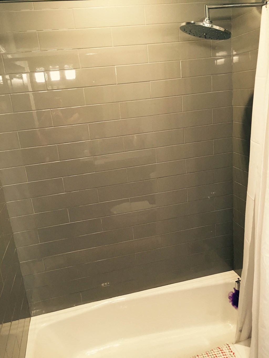 the shower has been tiled in gray subway tile