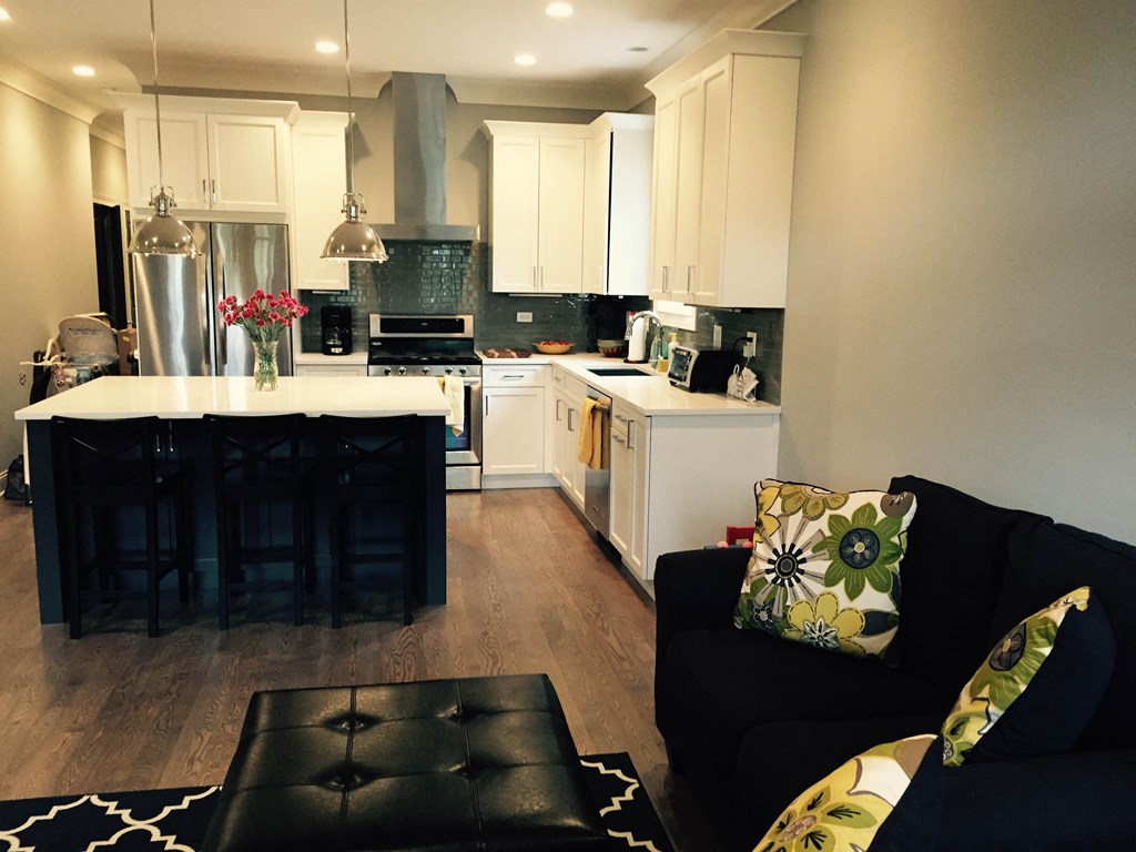 a kitchen and living room with a black couch and a white kitchen
