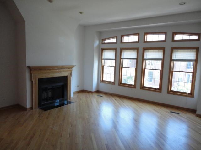an empty living room with a fireplace and wooden floors