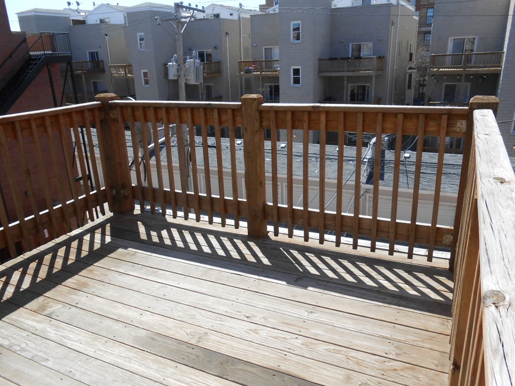 a deck with a wooden railing on top of a building