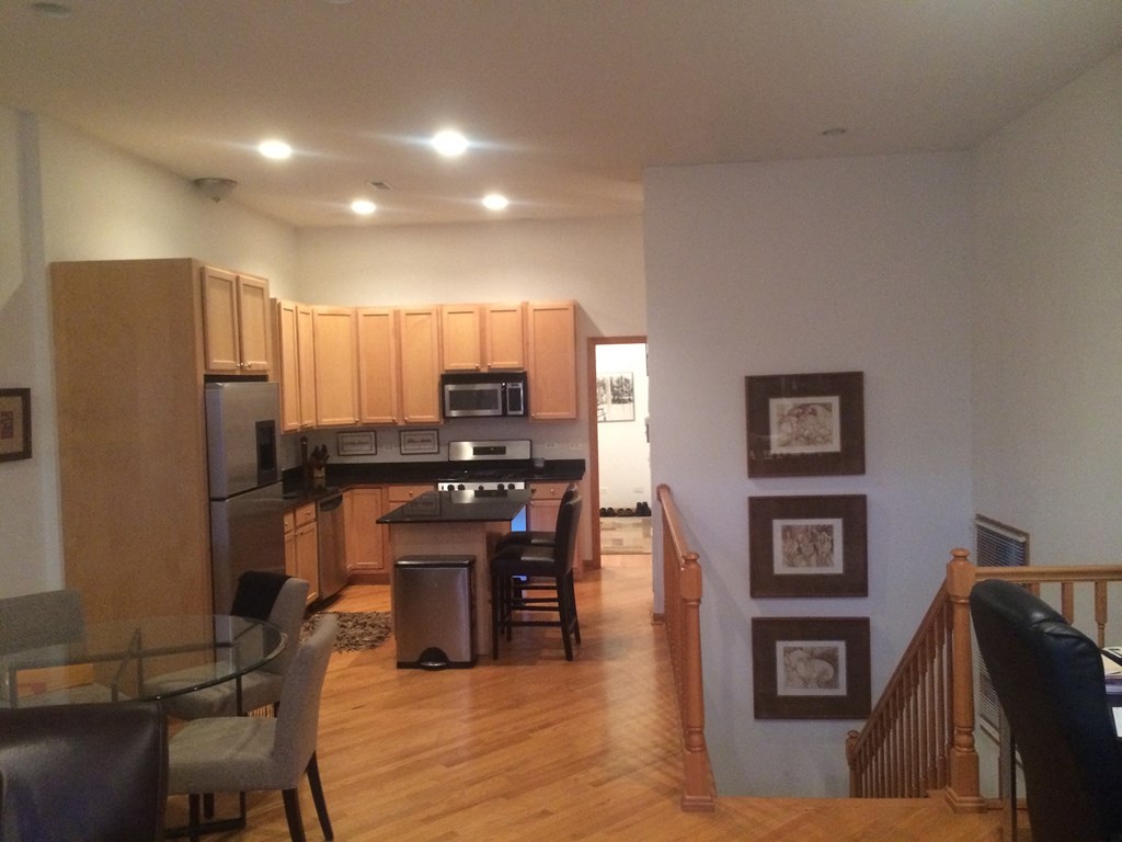 an open kitchen and living room with wooden floors and wooden cabinets