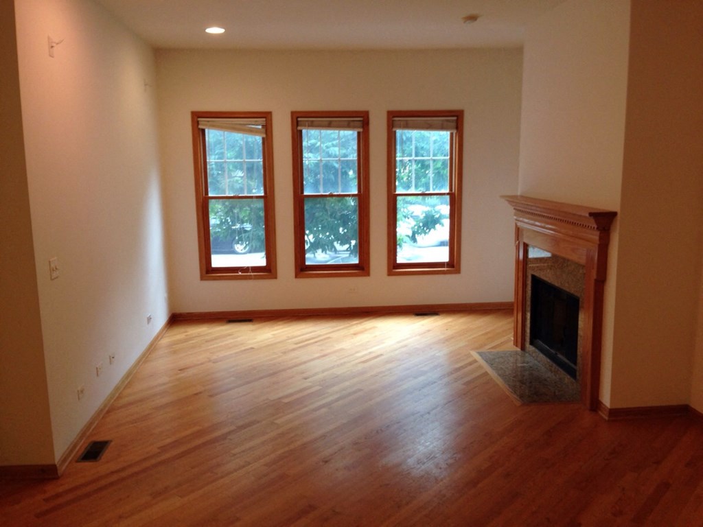 an empty living room with a fireplace and wooden floors