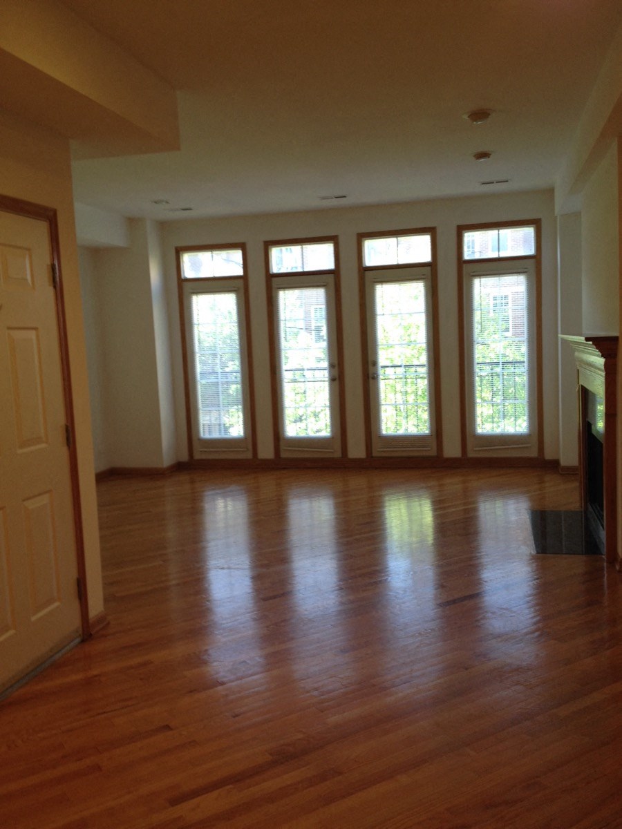 an empty living room with wood floors and large windows