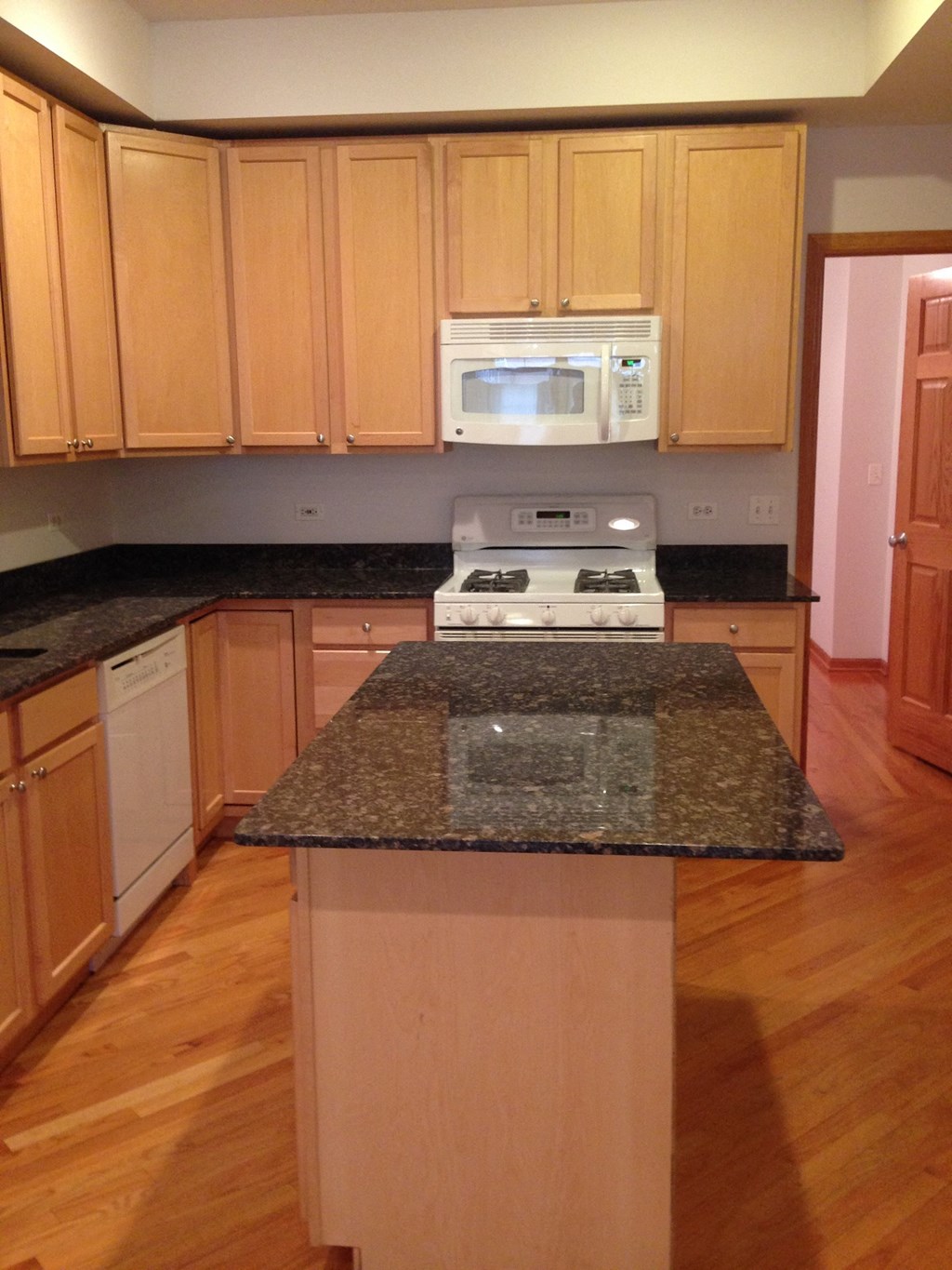 an empty kitchen with granite counter tops and wooden cabinets