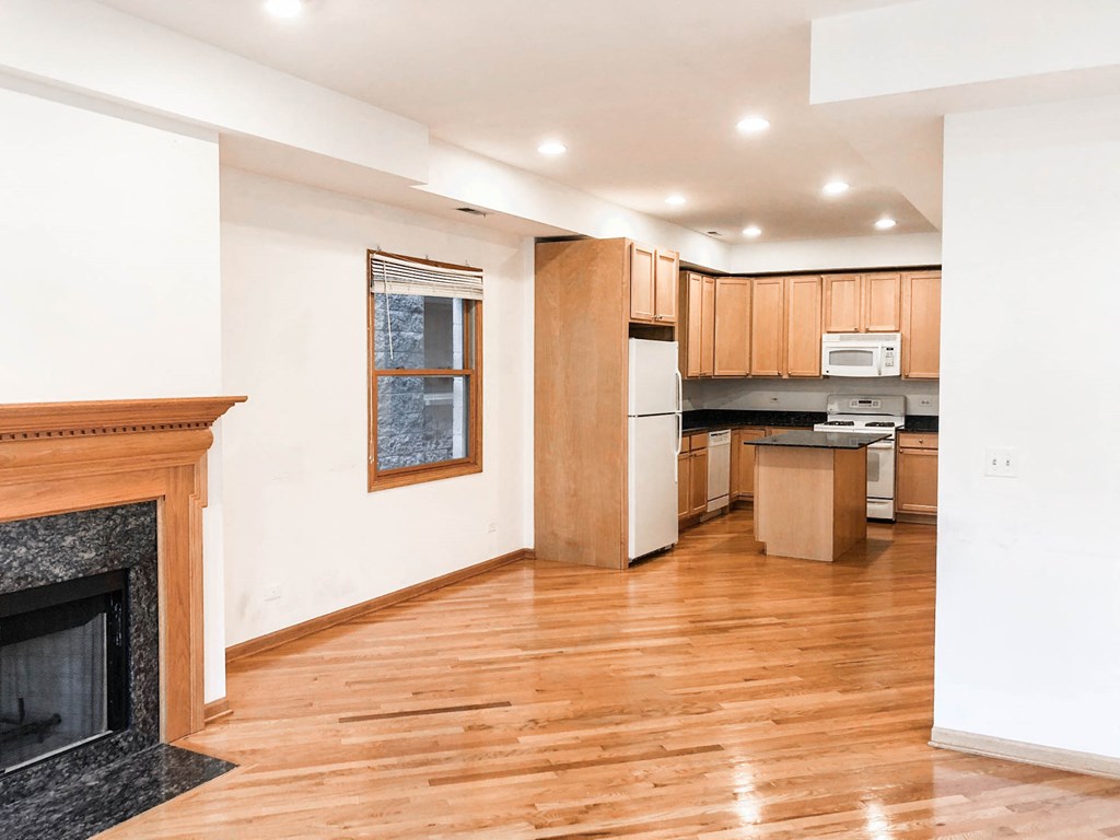 a living room with a fireplace and a kitchen with wooden cabinets