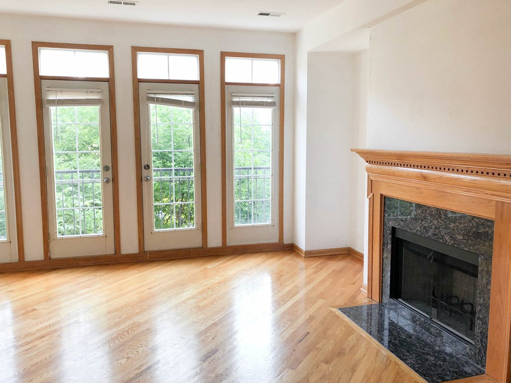 an empty living room with a fireplace and wood floors