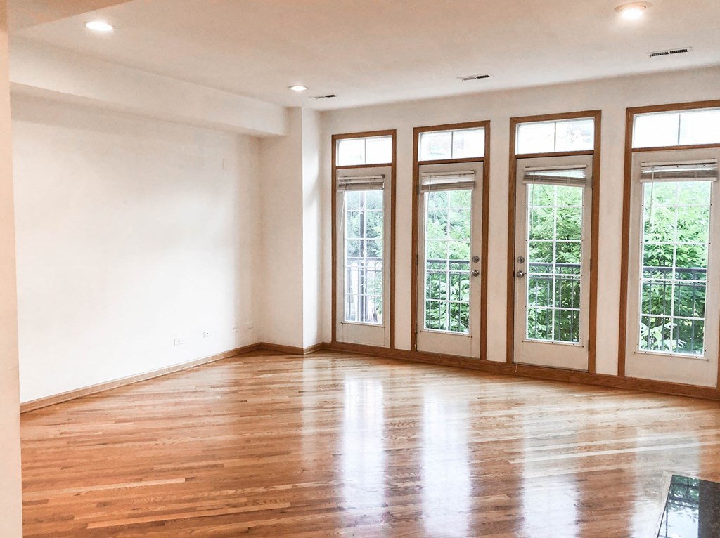 an empty living room with windows and wood floors