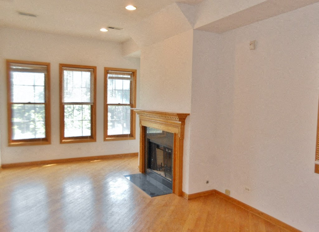 an empty living room with a fireplace and wood floors