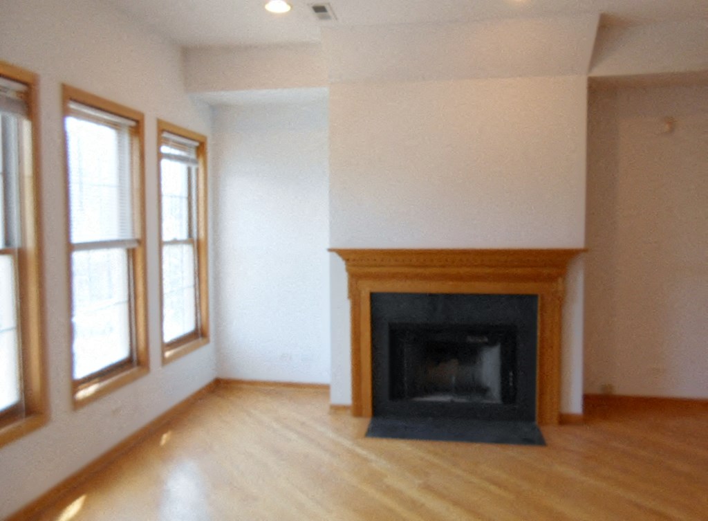 an empty living room with a fireplace and wooden floors