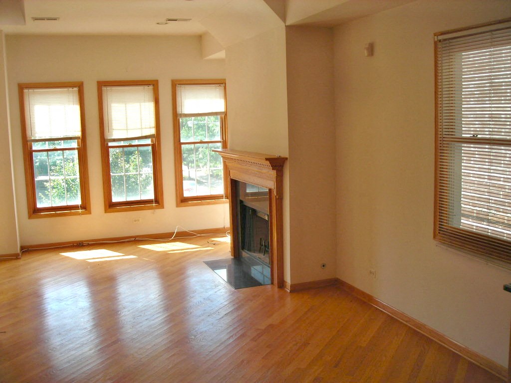 an empty living room with a fireplace and wood floors