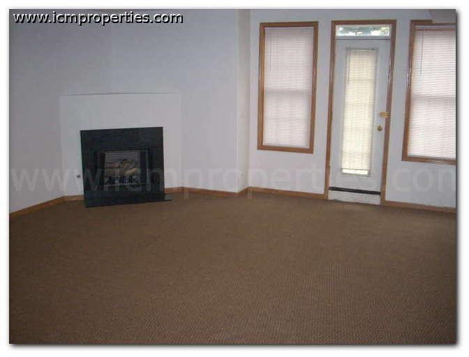 an empty living room with a fireplace and windows