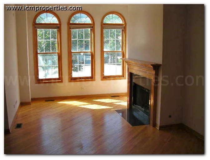 a empty living room with a fireplace and three windows