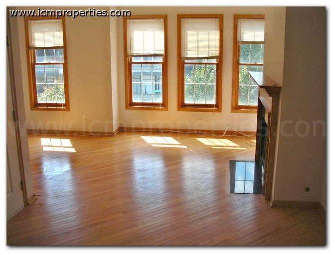 an empty living room with a wood floor and windows
