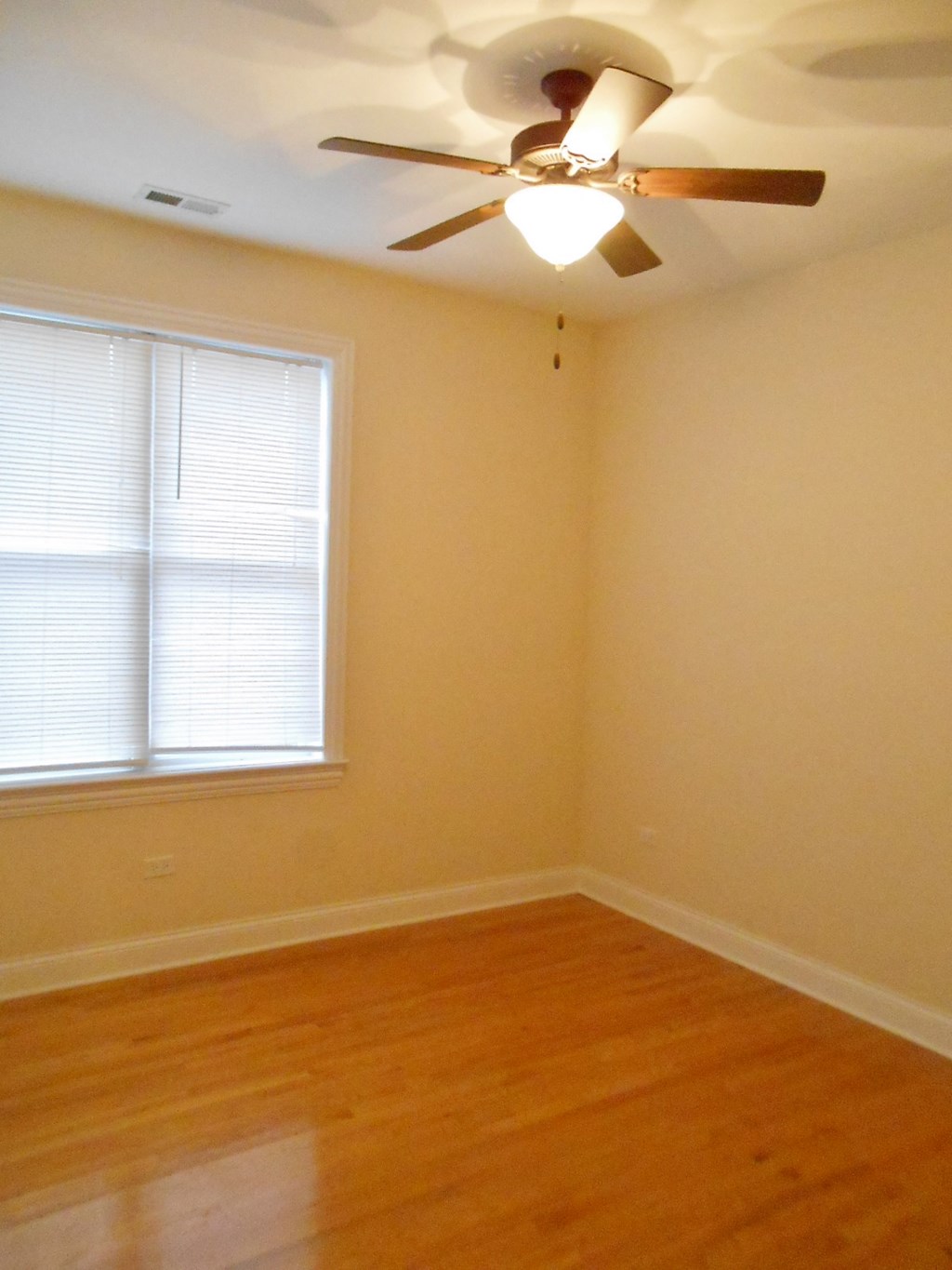 the corner of a room with a ceiling fan and a window