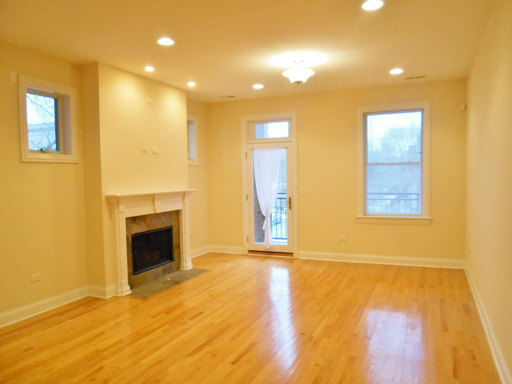 an empty living room with a fireplace and wooden floors