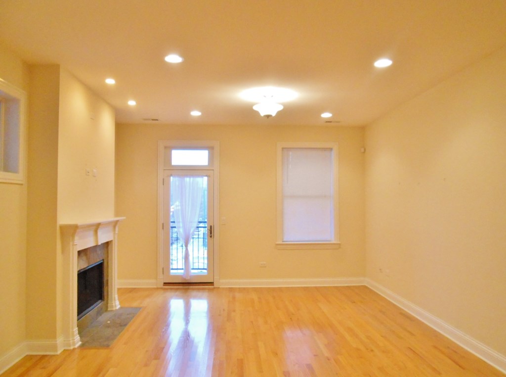an empty living room with a fireplace and wood floors